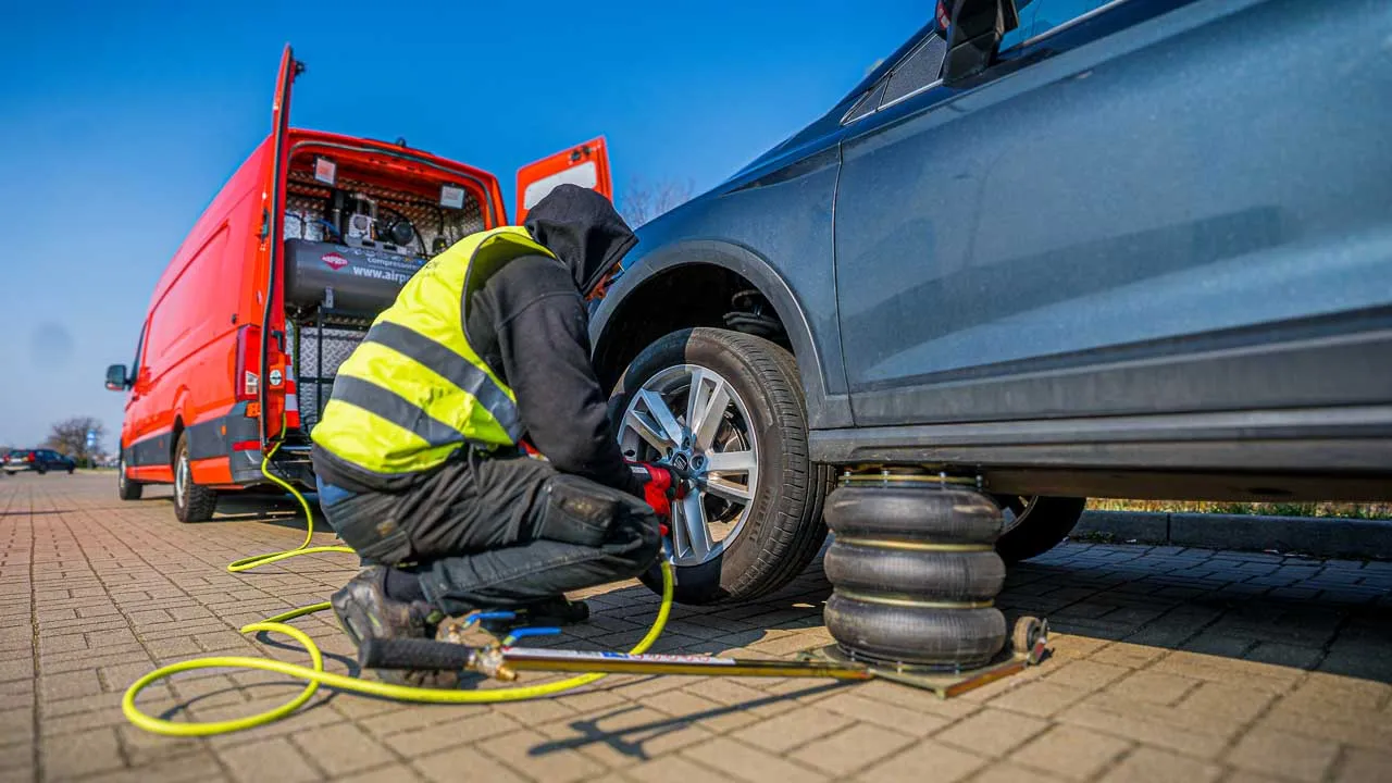 Montør skifter dæk på en personbil ved mobil dækservice